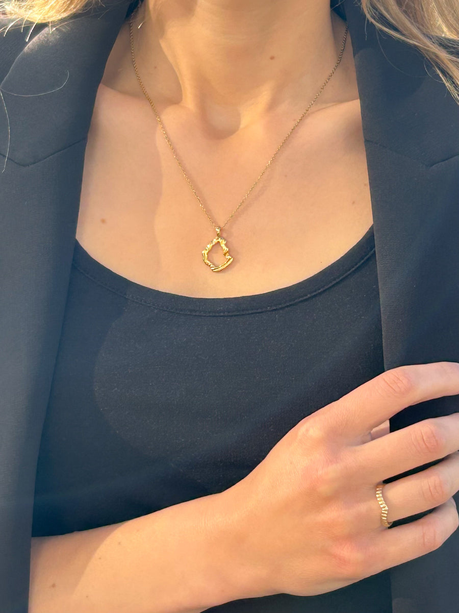 Shell fragment mirage pendant on model, wearing black top & blazer, & gold feather ring