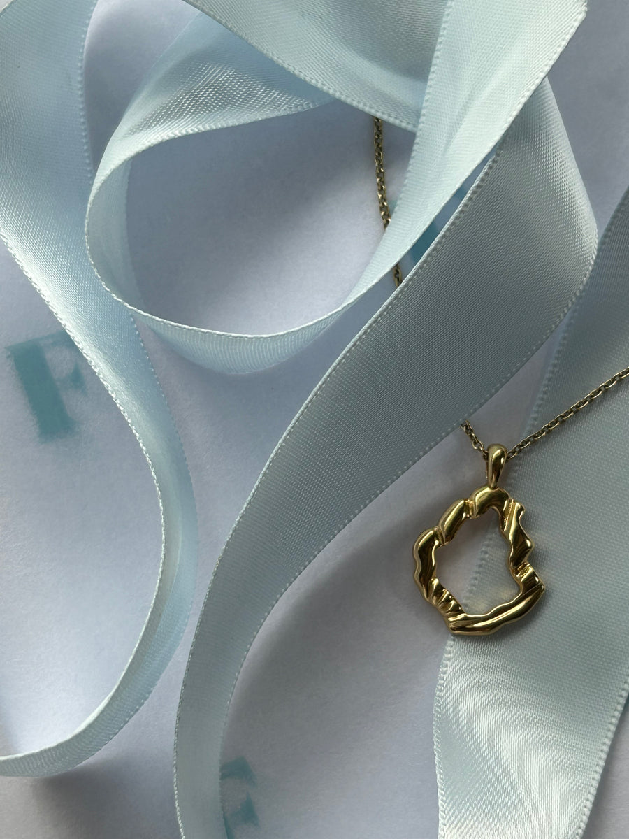 The Shell Fragment Mirage pendant, surrounded by blue ribbon.